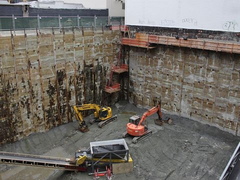 Tiefe Baugrube mit zwei Baggern und Förderband auf einer stillstehenden Baustelle
