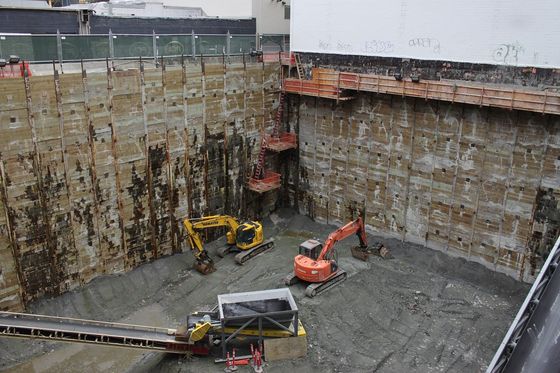 Tiefe Baugrube mit zwei Baggern und Förderband auf einer stillstehenden Baustelle